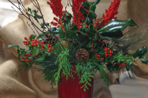 A photo of a red book with evergreens and other floral decorations.